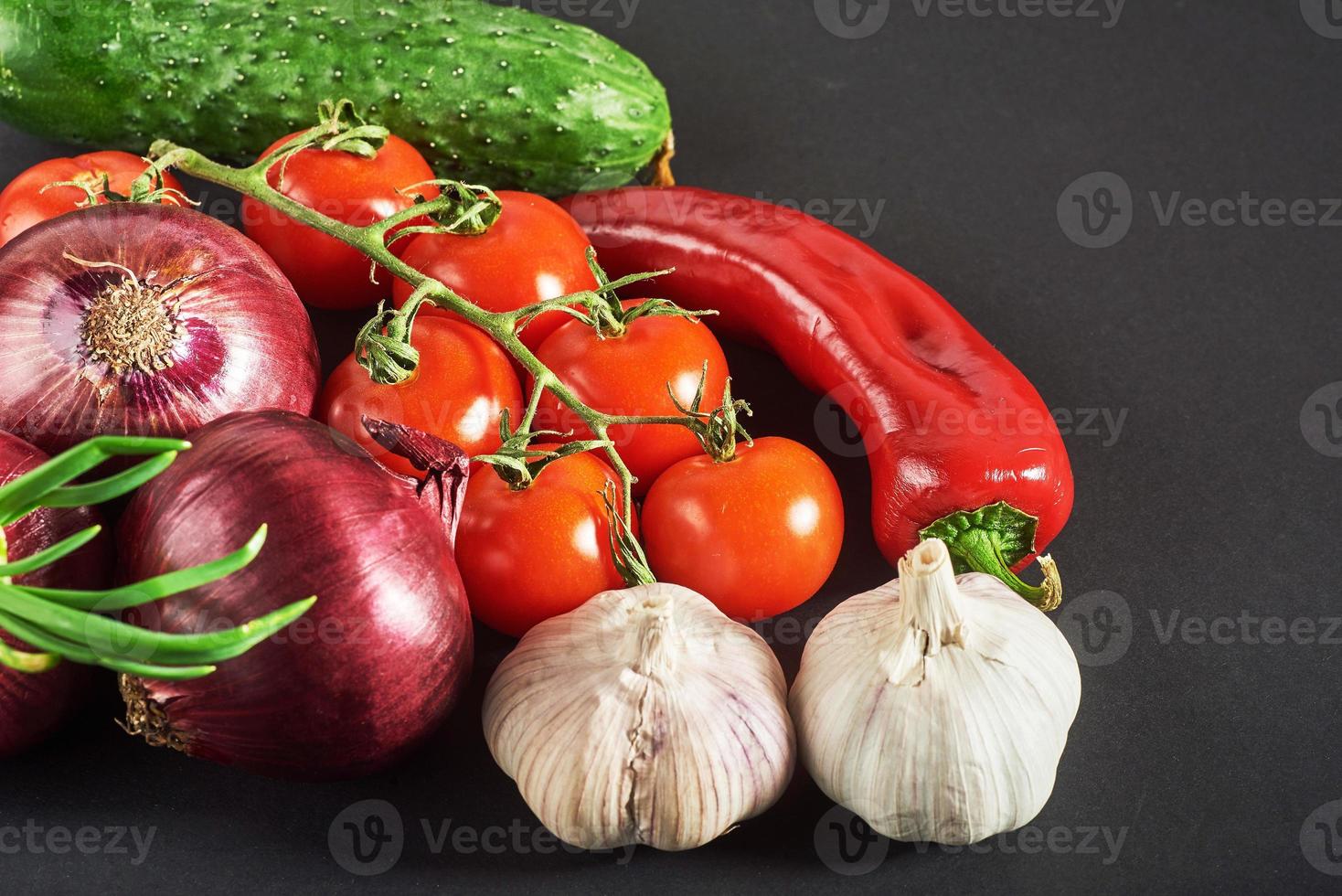 blue onion and garlic, tomato and cucumber on a black background. photo