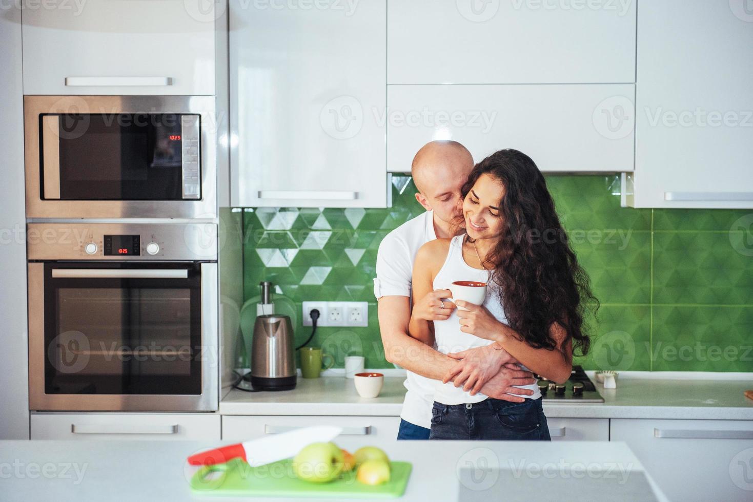 Happy young couple having coffee in the kitchen photo