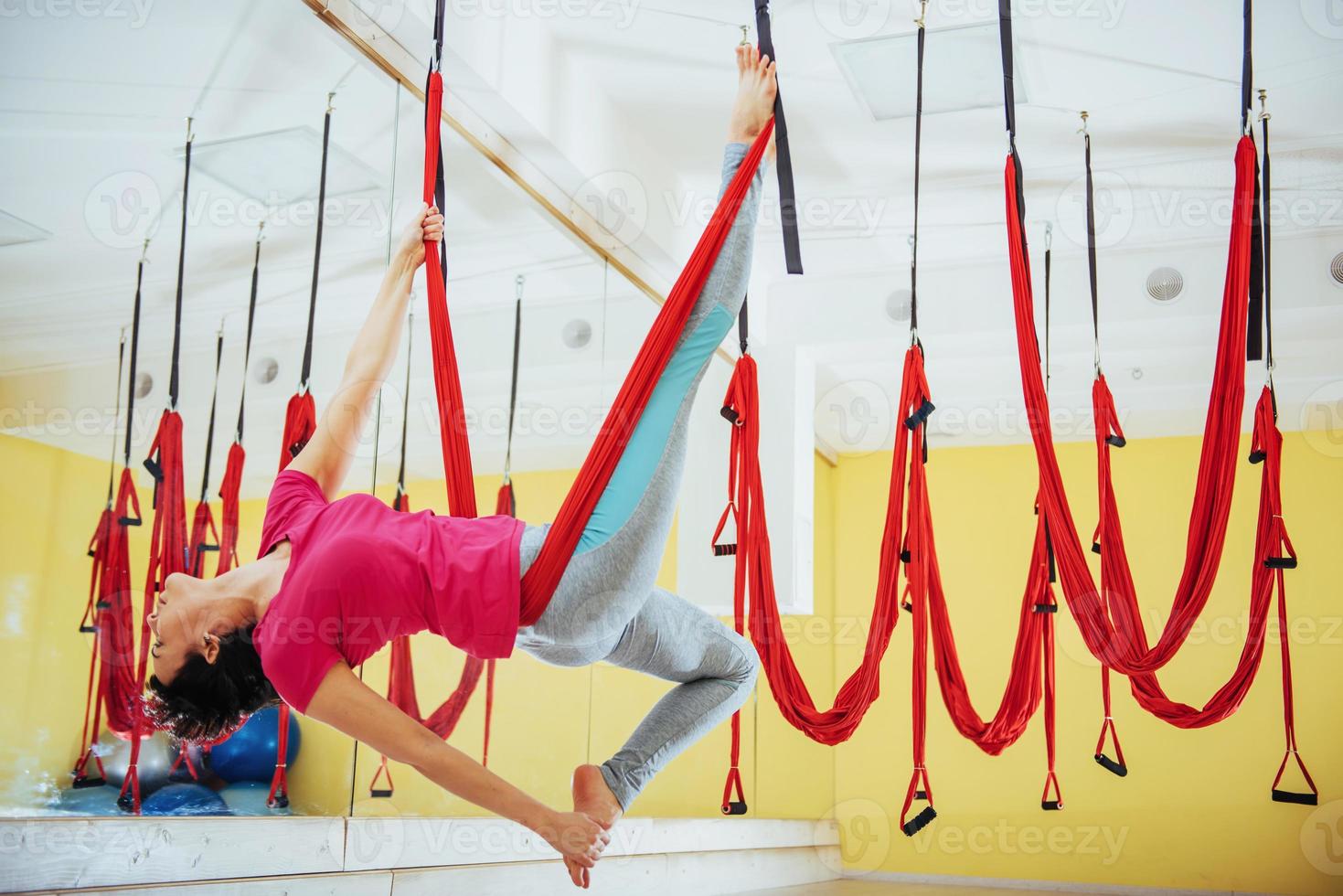 joven hermosa mujer practicando yoga volar con una hamaca en el estudio. foto