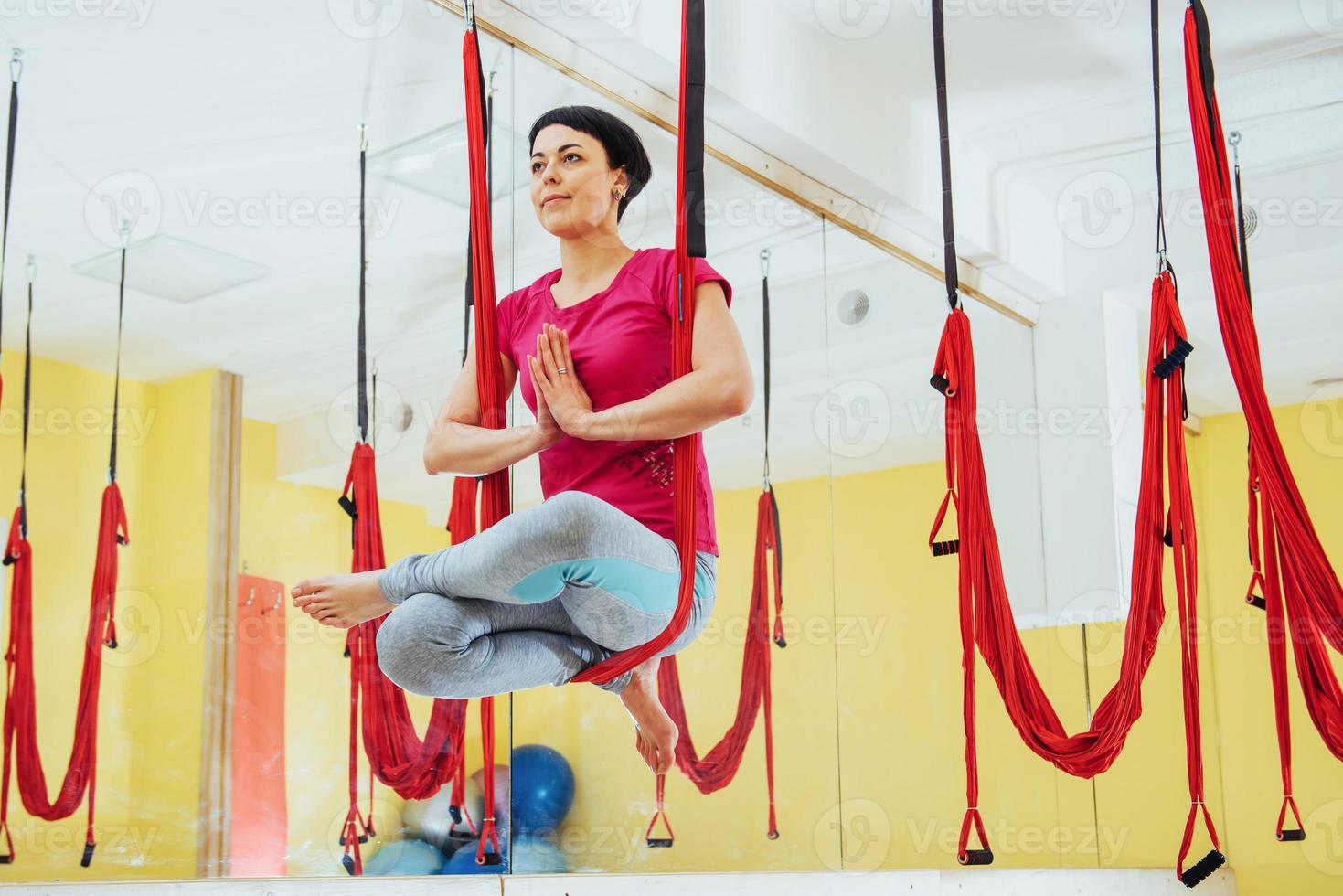 Young beautiful woman practicing yoga Fly with a hammock in the bright studio. The concept of mental and physical health. photo