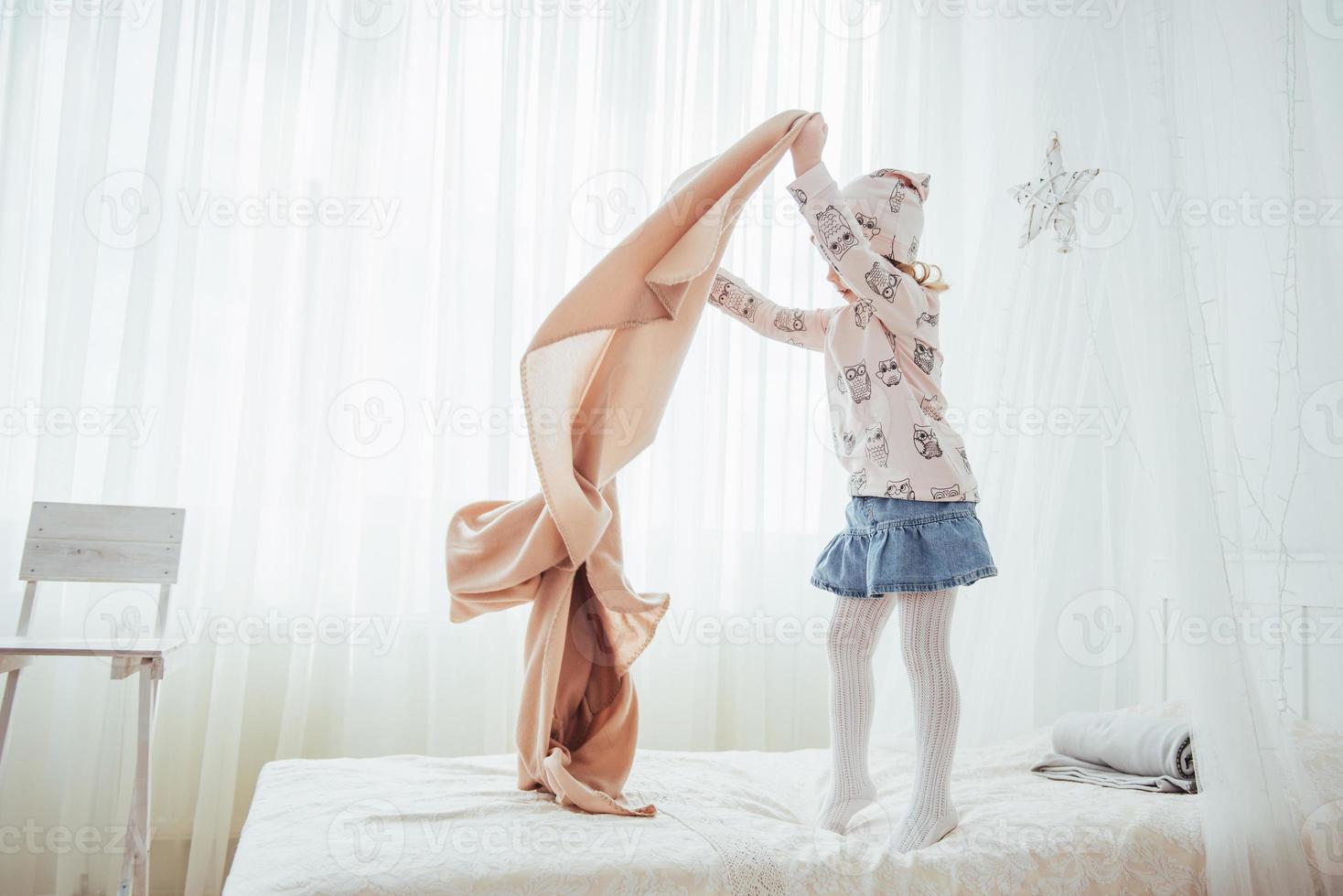 The little girl wants to wrap in a blanket in the bedroom light photo