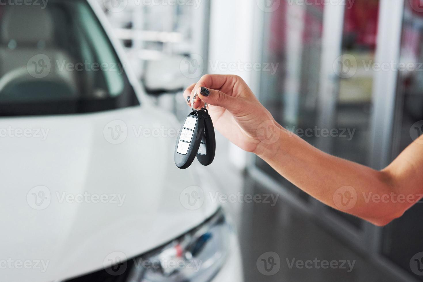 pasando las llaves del coche. Primer plano recortado de un concesionario de automóviles que sostiene las llaves del automóvil a la cámara. foto