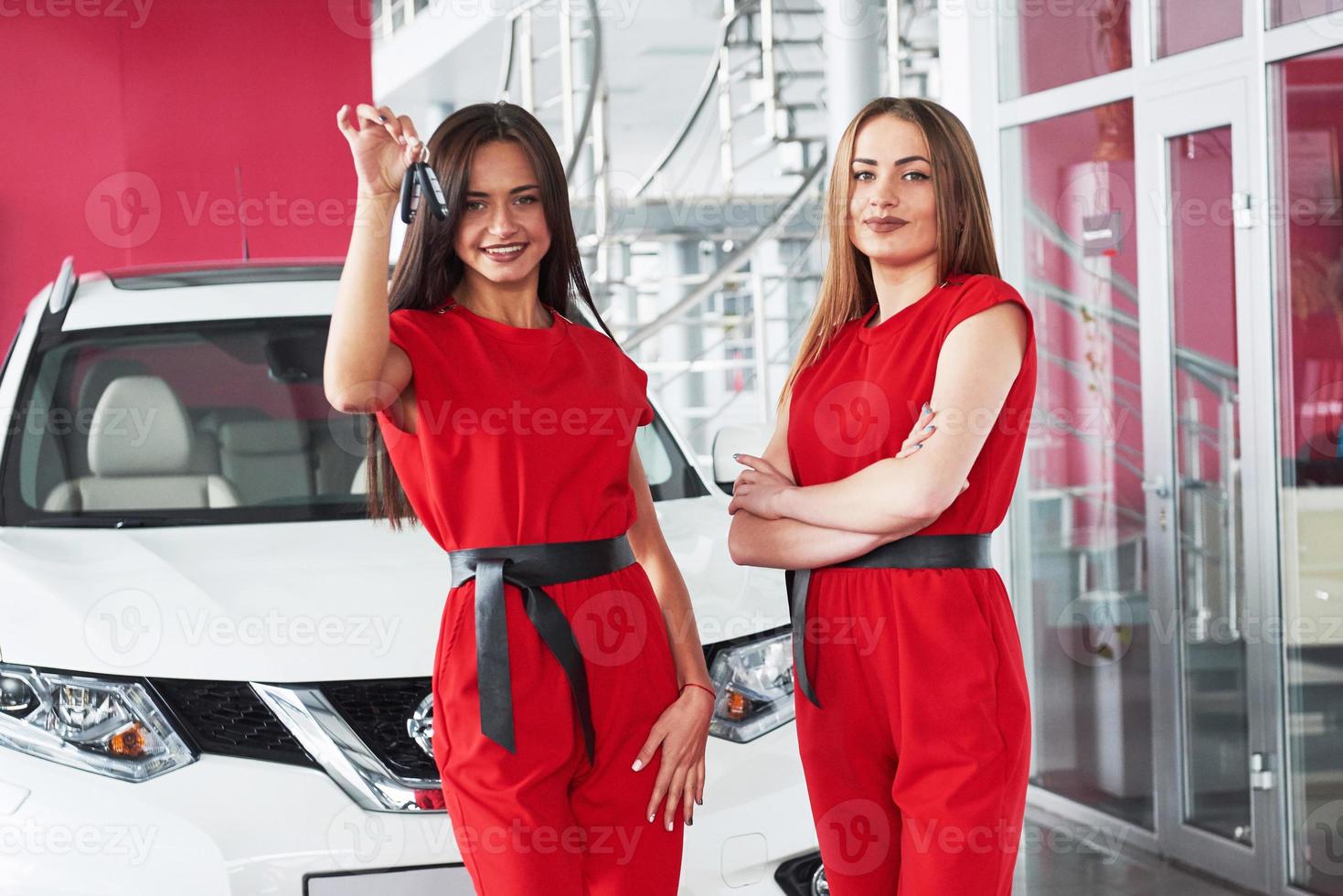 joven feliz dos mujeres cerca del auto con las llaves en la mano - concepto de comprar auto. foto