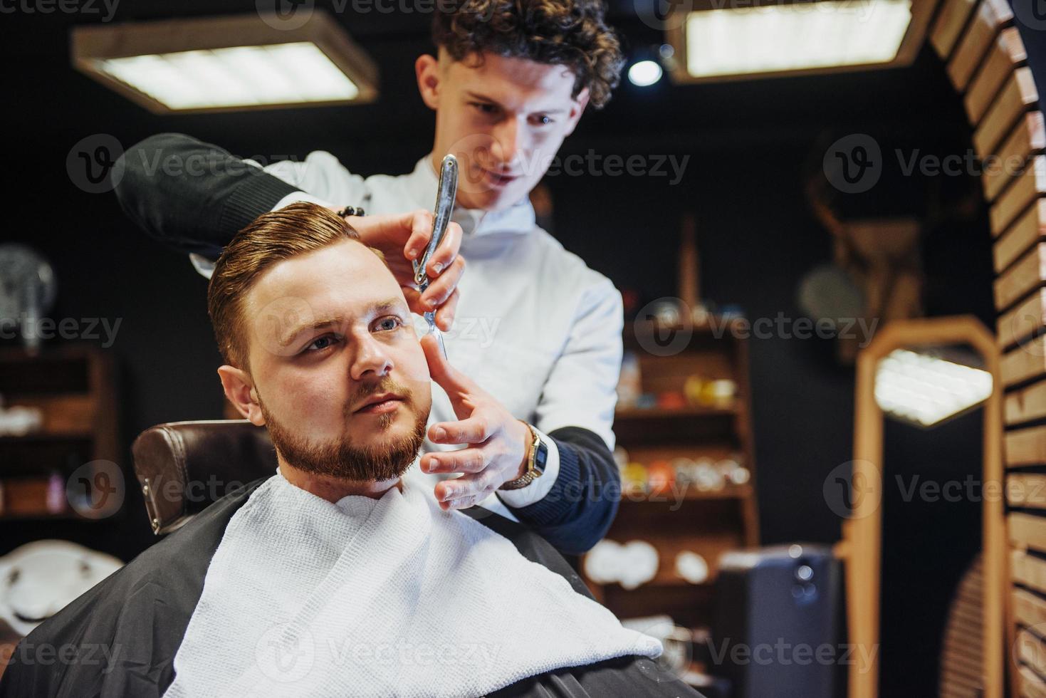 hombre peluquero haciendo corte de pelo barba hombres adultos en la peluquería de hombres foto