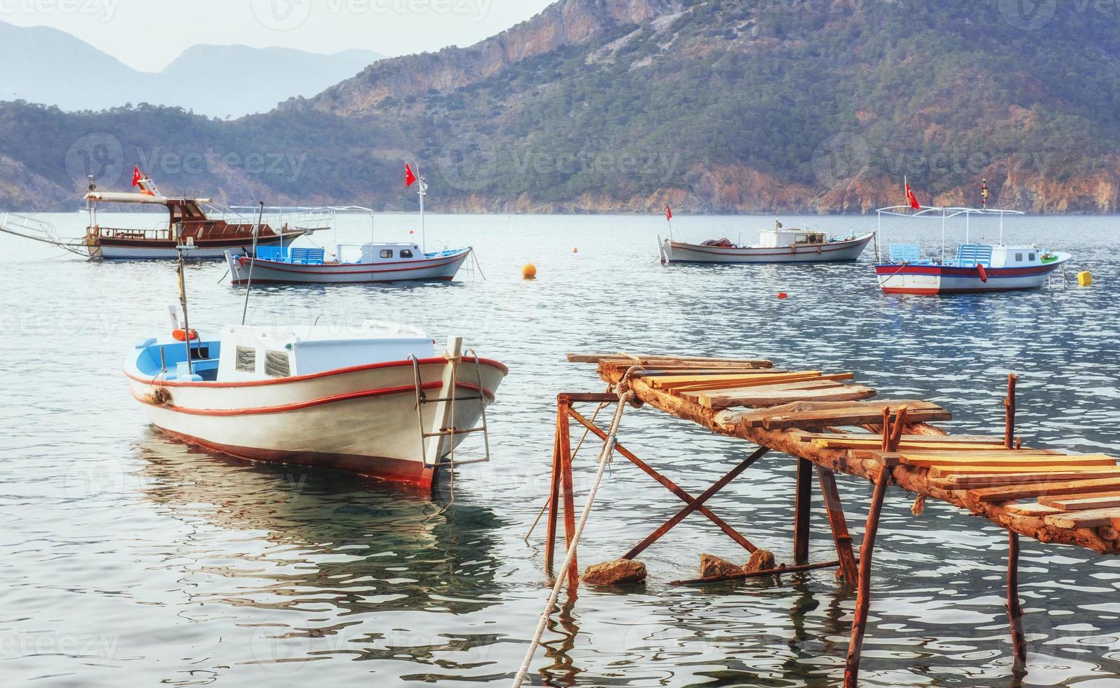 Boats near the broken pier, putting in a tranquil calm blue sea water photo