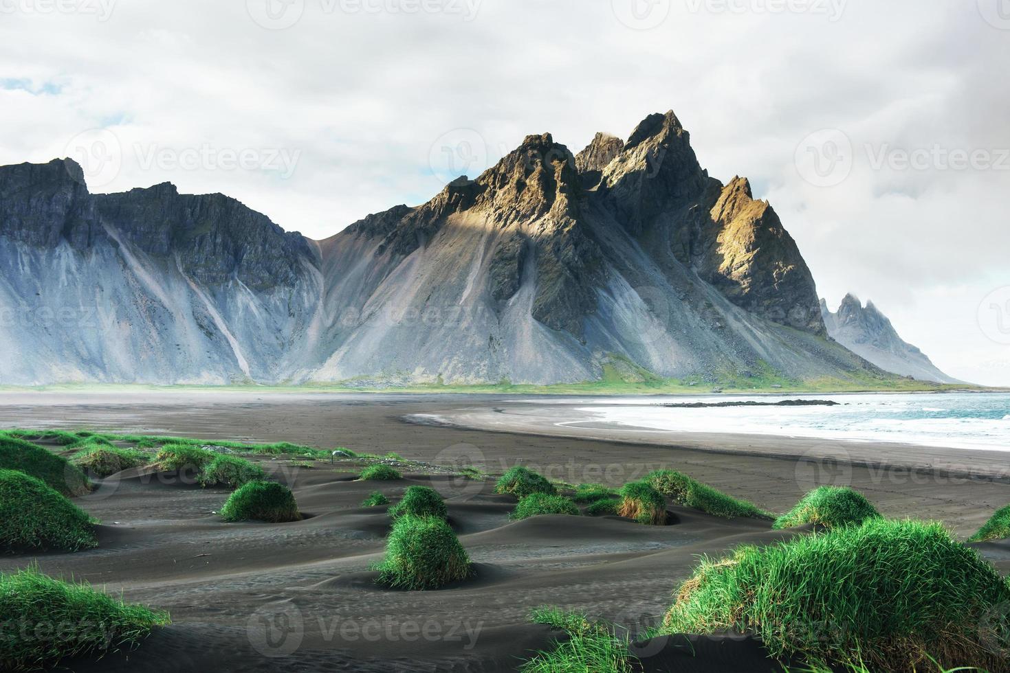 fantástico oeste de las montañas y dunas de arena de lava volcánica en la playa stokksness, islandia. foto