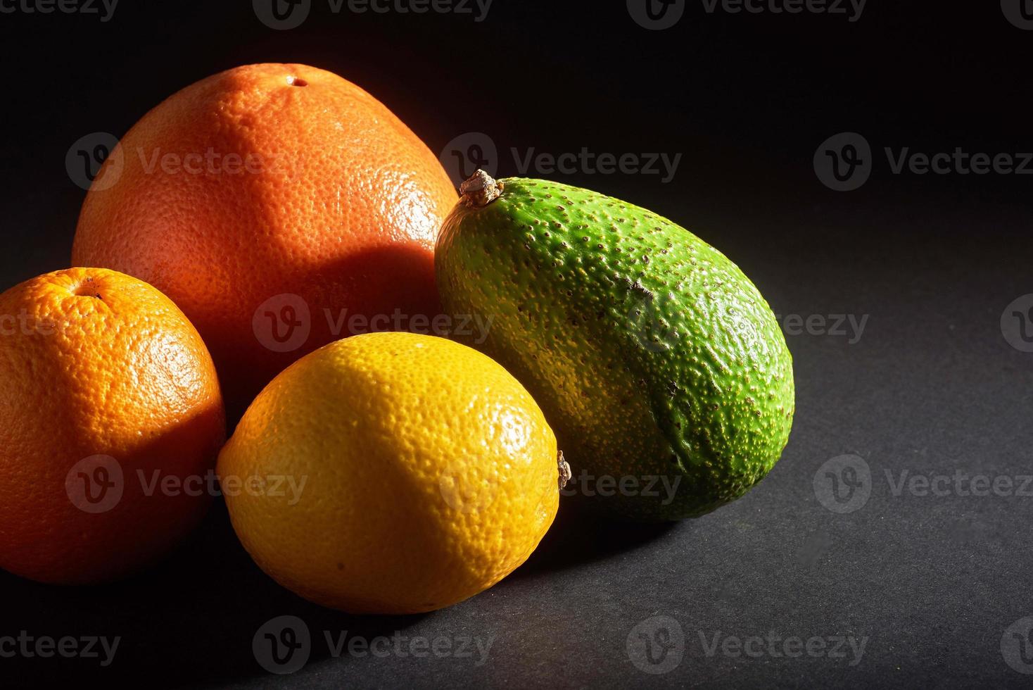 Delicious fresh orange, grapefruit, avocado, lemon isolated on a black background. photo