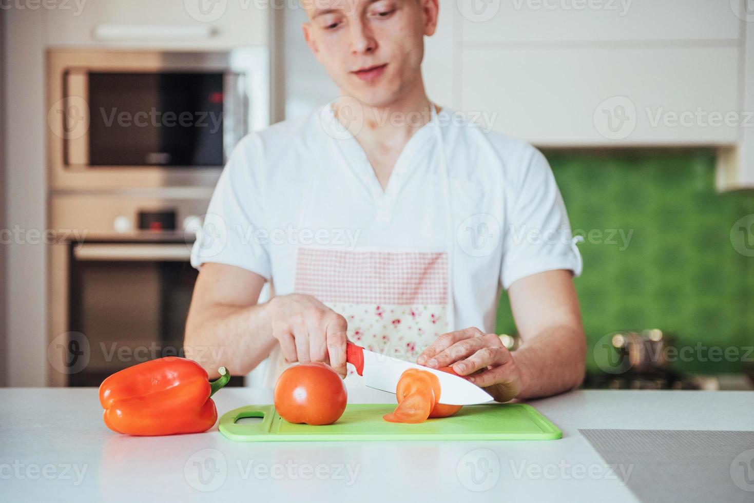 man cuts vegetables together in the kitchen photo
