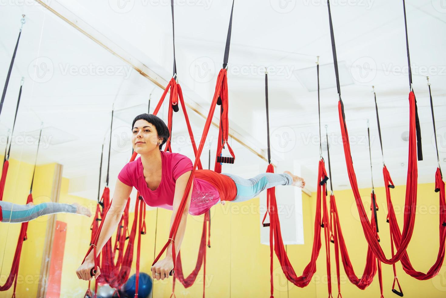 Young beautiful woman practicing yoga Fly with a hammock in the bright studio. The concept of mental and physical health. photo