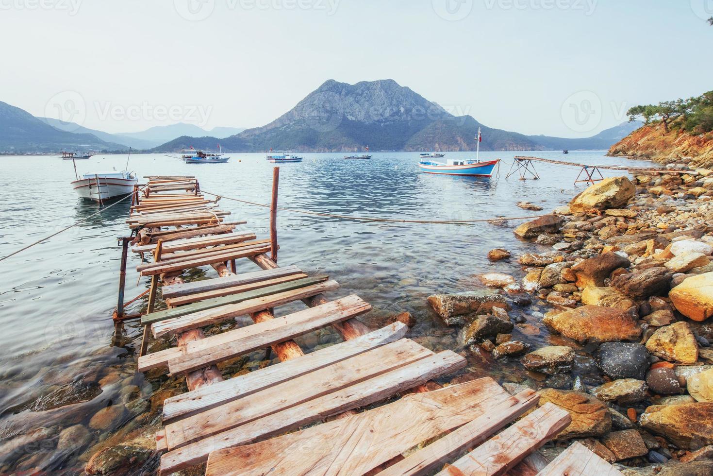 barcos cerca del muelle roto, poniendo en un mar azul tranquilo y tranquilo foto