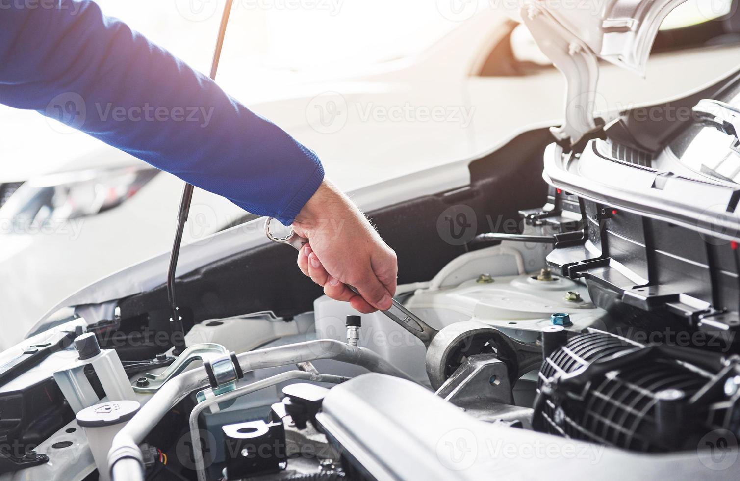 Hands of car mechanic with wrench in garage photo