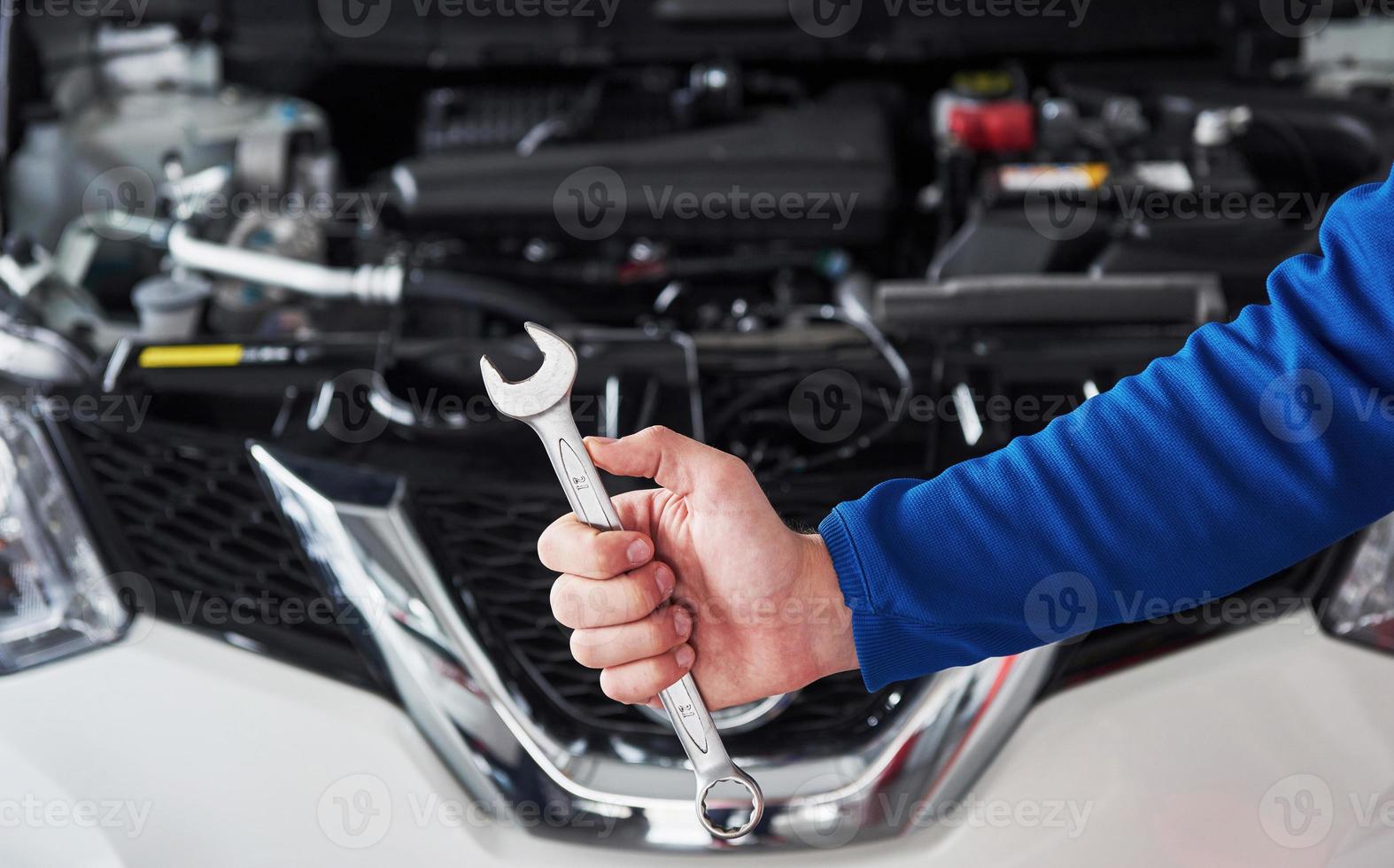 Hands of car mechanic with wrench in garage photo