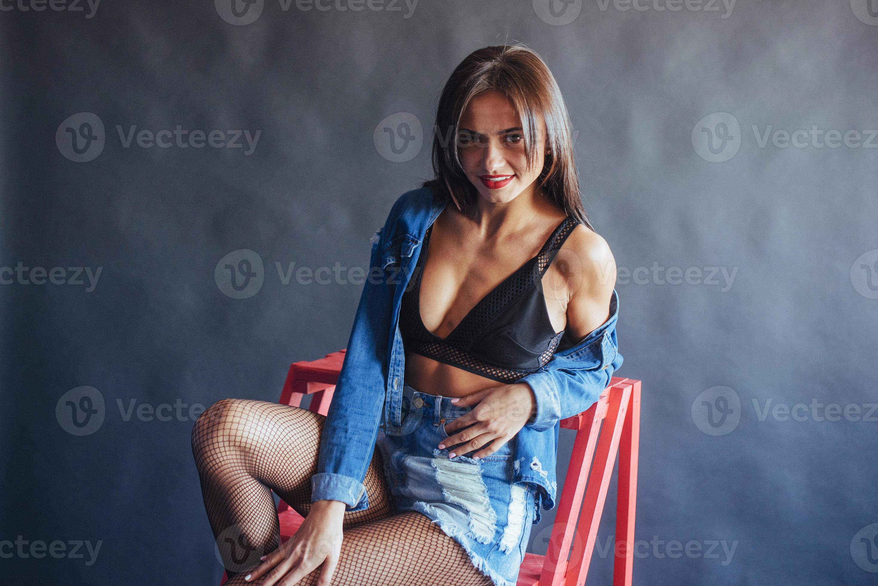 Fashionable brunette beautiful woman posing in studio wearing short jeans