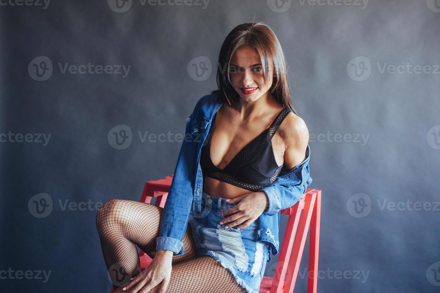 Fashionable brunette beautiful woman posing in studio wearing short jeans. photo