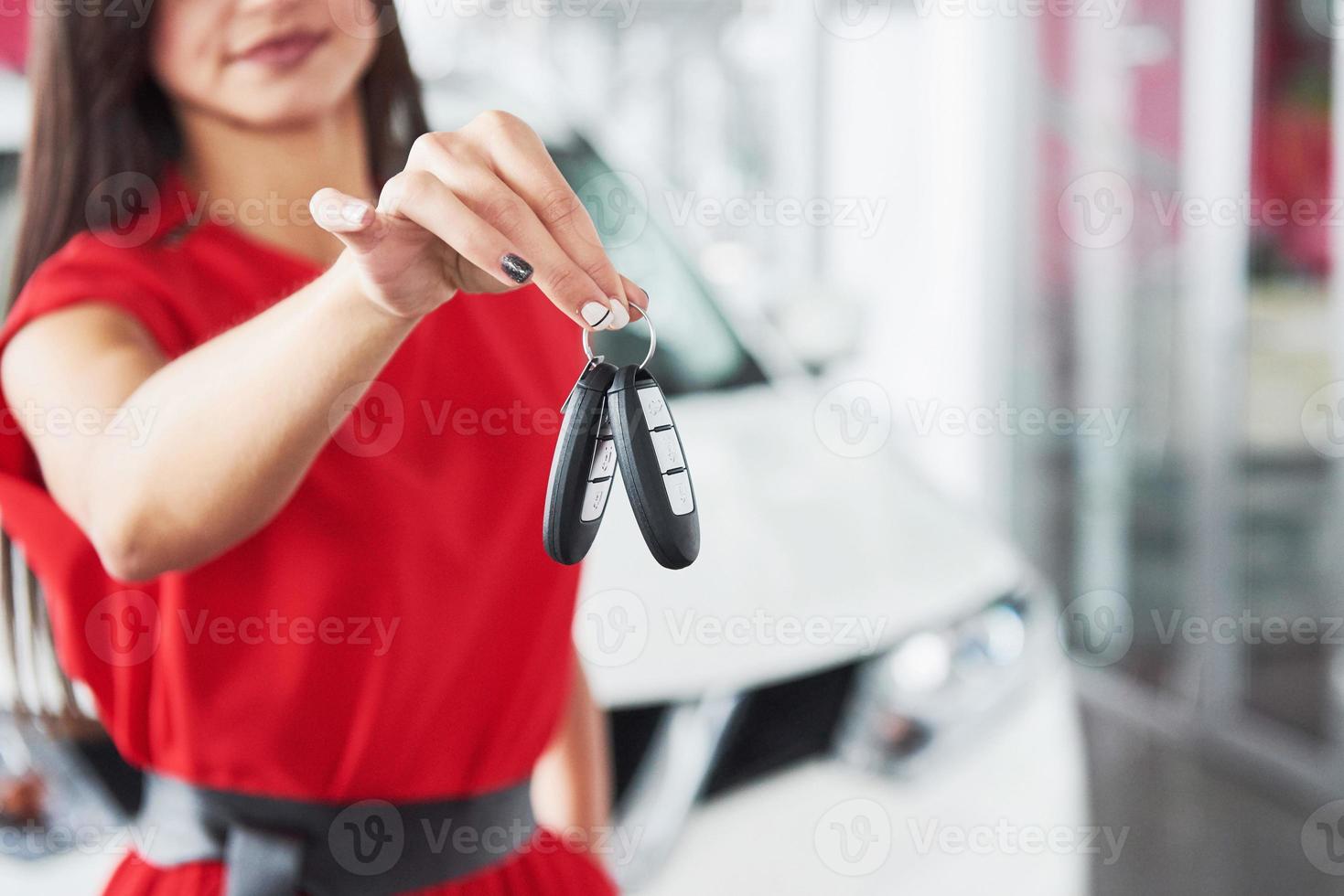 vendedor de autos sonriente entregando las llaves de su nuevo auto, concesionario y concepto de ventas. niña feliz el comprador foto