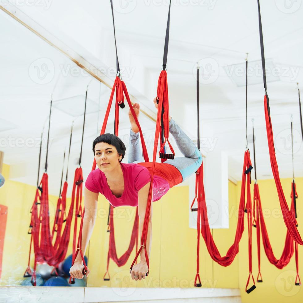 Young beautiful woman practicing yoga Fly with a hammock in the bright studio. The concept of mental and physical health. photo