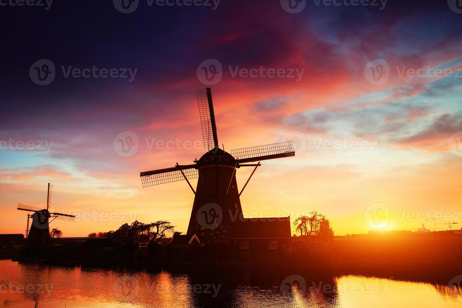 Landscape with beautiful traditional Dutch mill near water courses with fantastic sunset and reflection in water. Netherlands. photo