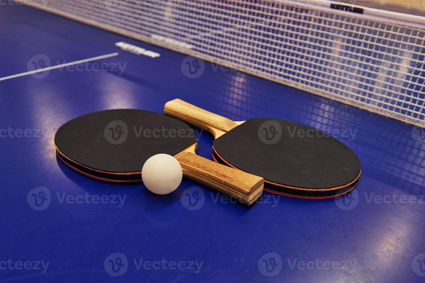 Table tennis racket with a ball on a blue table photo