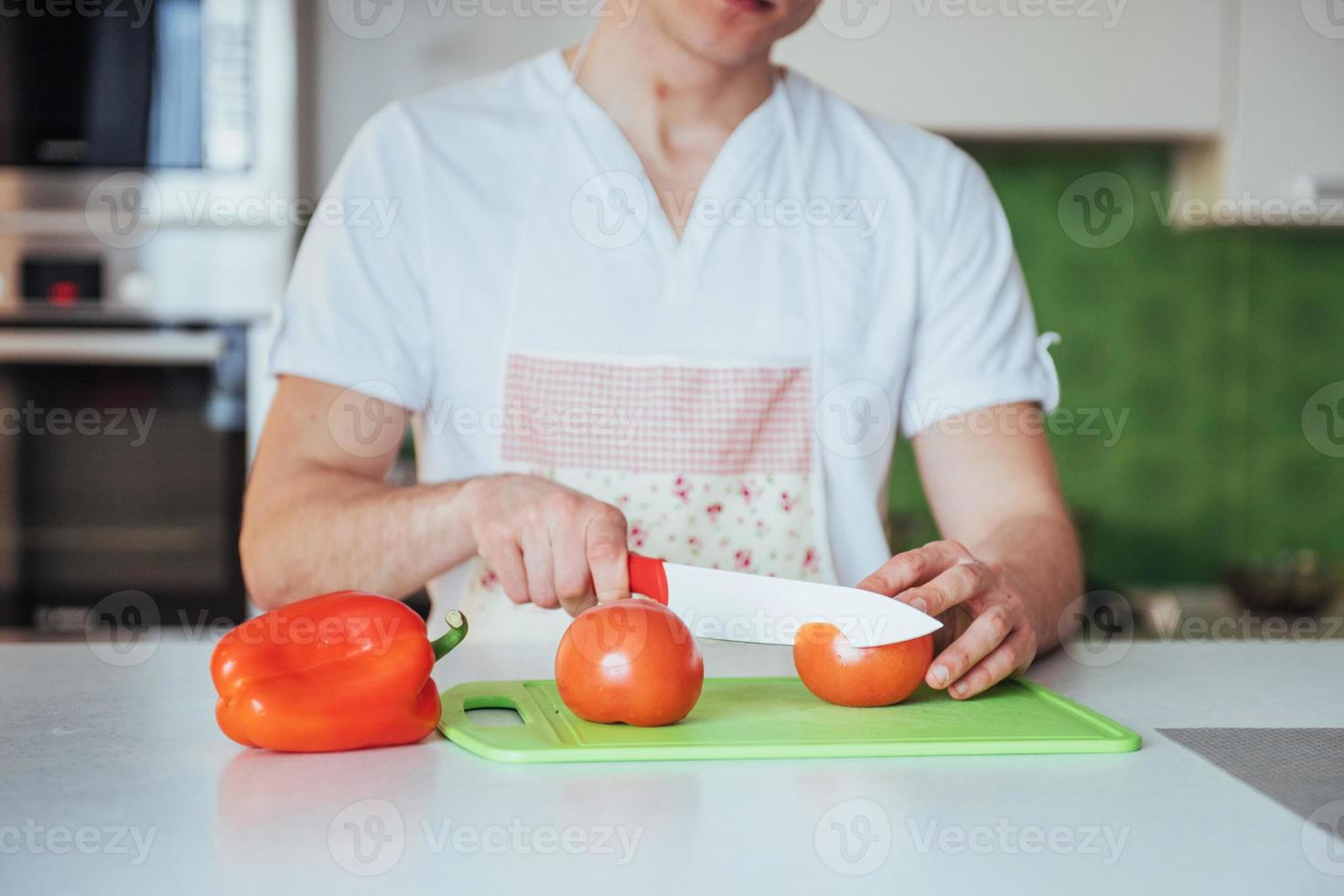 man cuts vegetables together in the kitchen photo