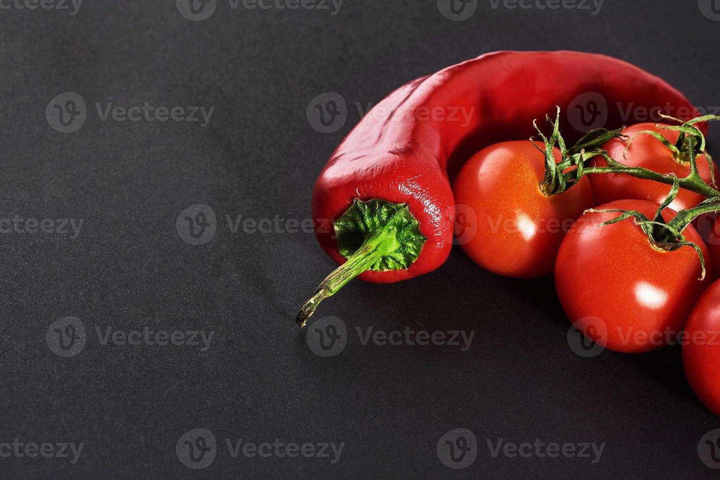 branch of tomatoes and red chili peppers, isolated on a black background photo