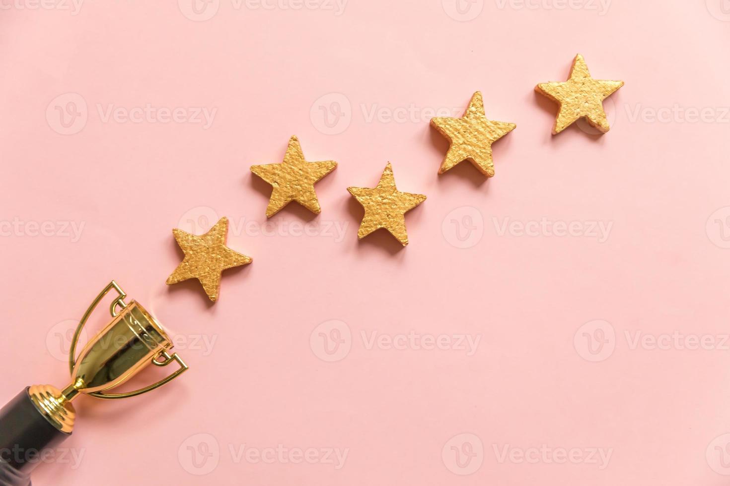 Simply flat lay design winner or champion gold trophy cup and 5 stars rating isolated on pink pastel background. Victory first place of competition. Winning or success concept. Top view, copy space photo