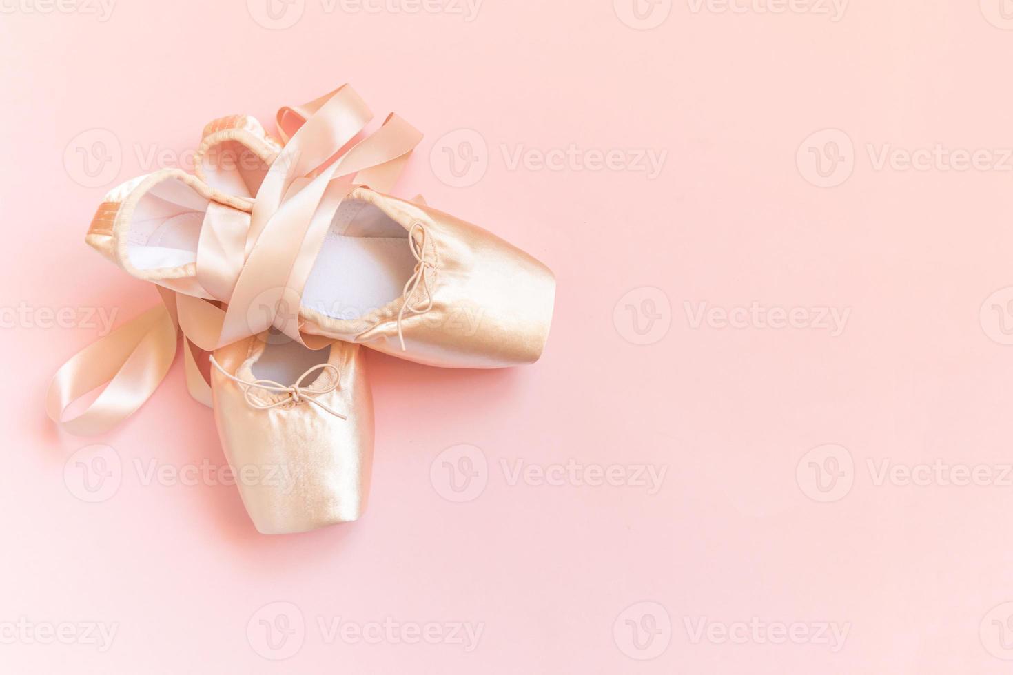 New pastel beige ballet shoes with satin ribbon isolated on pink background. Ballerina classical pointe shoes for dance training. Ballet school concept. Top view flat lay, copy space photo