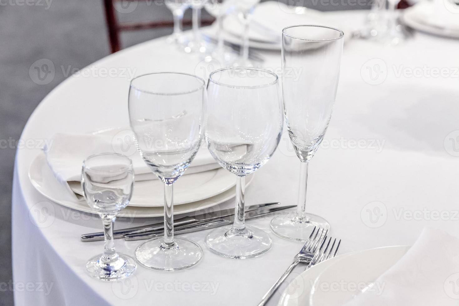 Fancy table set for dinner with napkin glasses in restaurant, luxury interior background. Wedding elegant banquet decoration and items for food arranged by catering service on white tablecloth table. photo