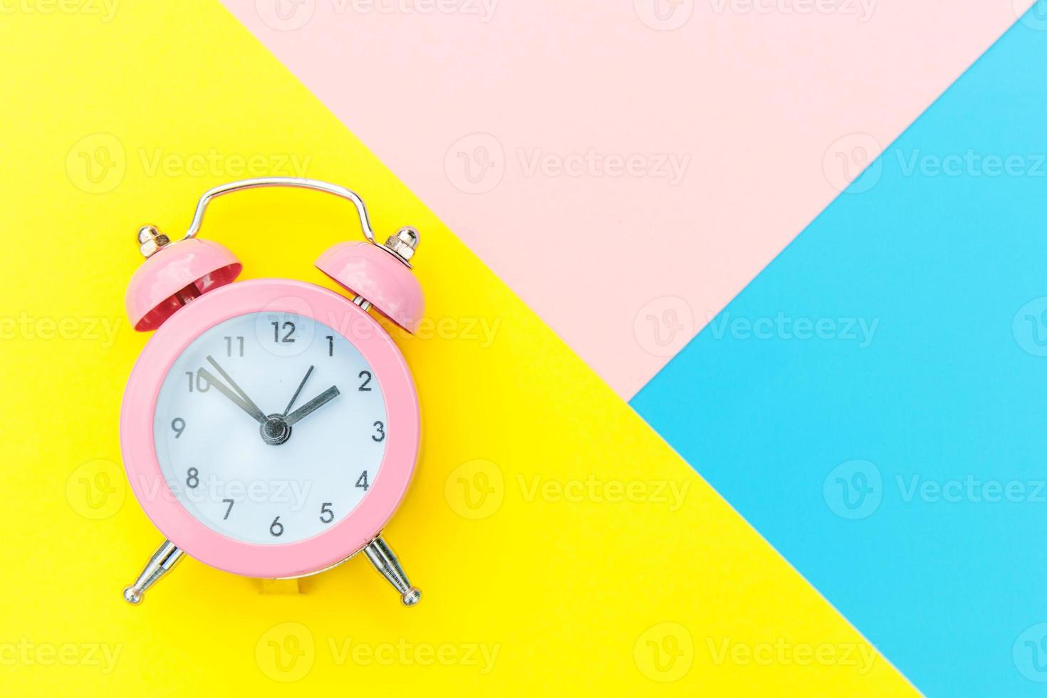 Ringing twin bell classic alarm clock isolated on blue yellow pink pastel colorful geometric background. Rest hours time of life good morning night wake up awake concept. Flat lay top view copy space. photo