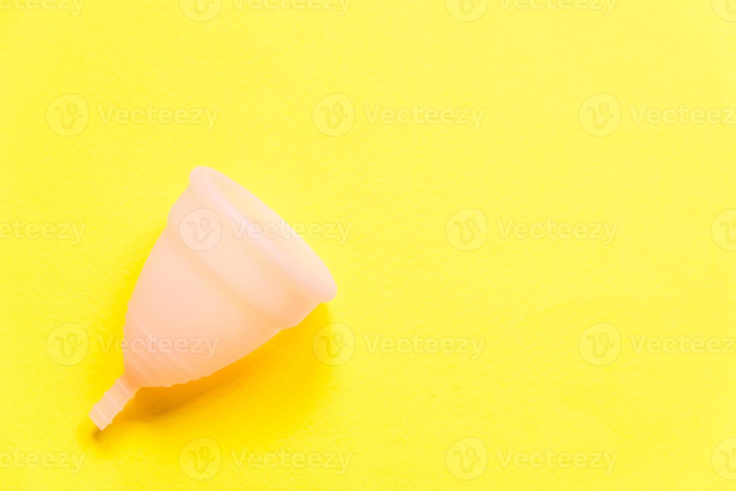 Simply minimal design pink menstrual cup Isolated on yellow background. Woman modern alternative eco gynecological hygiene in menstruation period. Container for blood. Flat lay top view, copy space photo