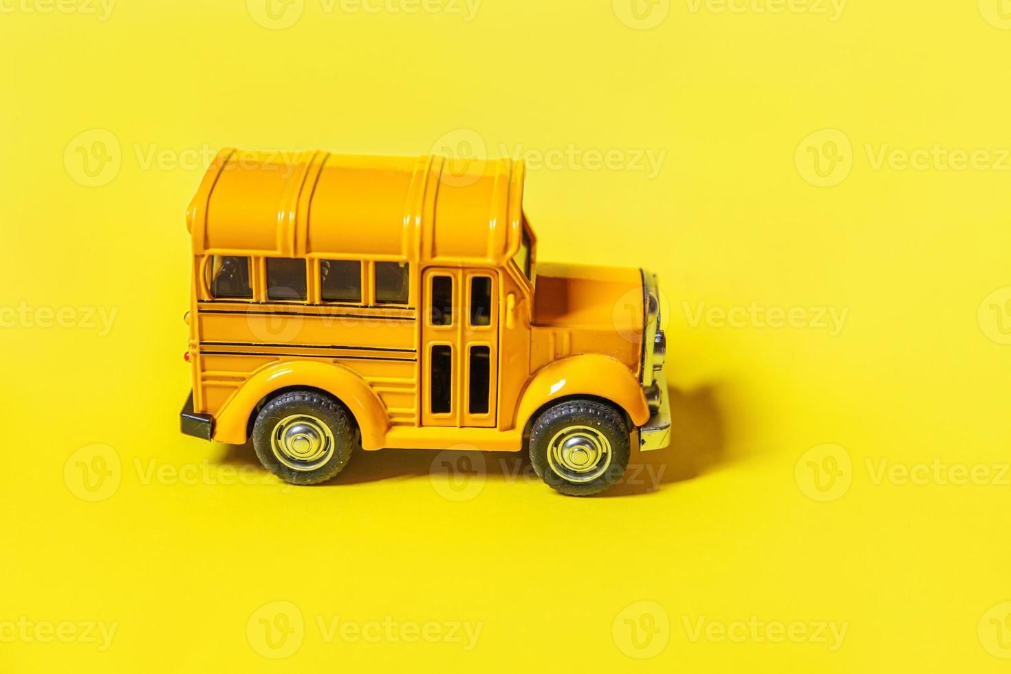 Simply design yellow classic toy car school bus isolated on yellow colorful background. Safety daily transport for kids. Back to school concept. Education symbol, copy space photo