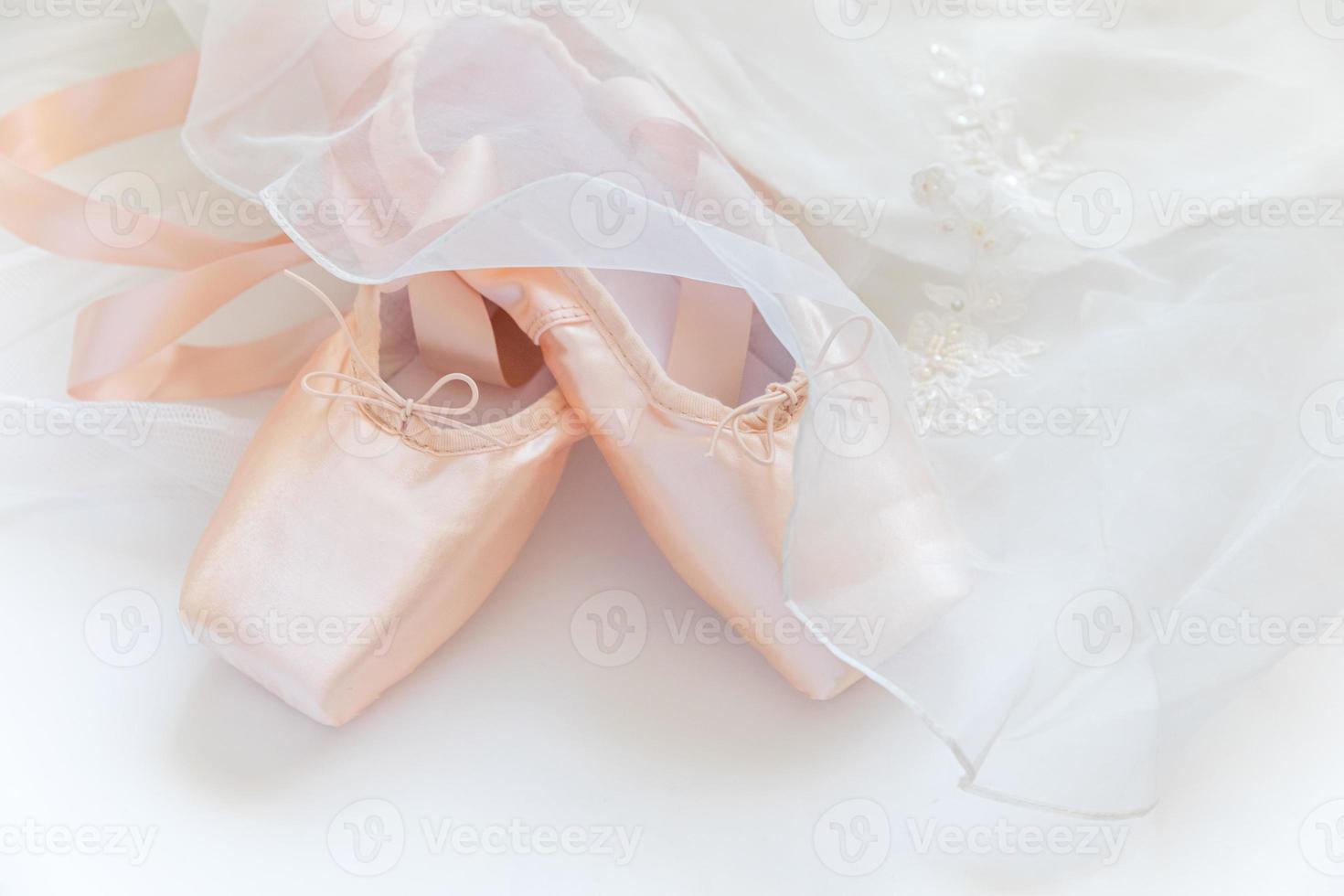 New pastel beige ballet shoes with satin ribbon and tutut skirt isolated on white background. Ballerina classical pointe shoes for dance training. Ballet school concept. Top view flat lay, copy space photo