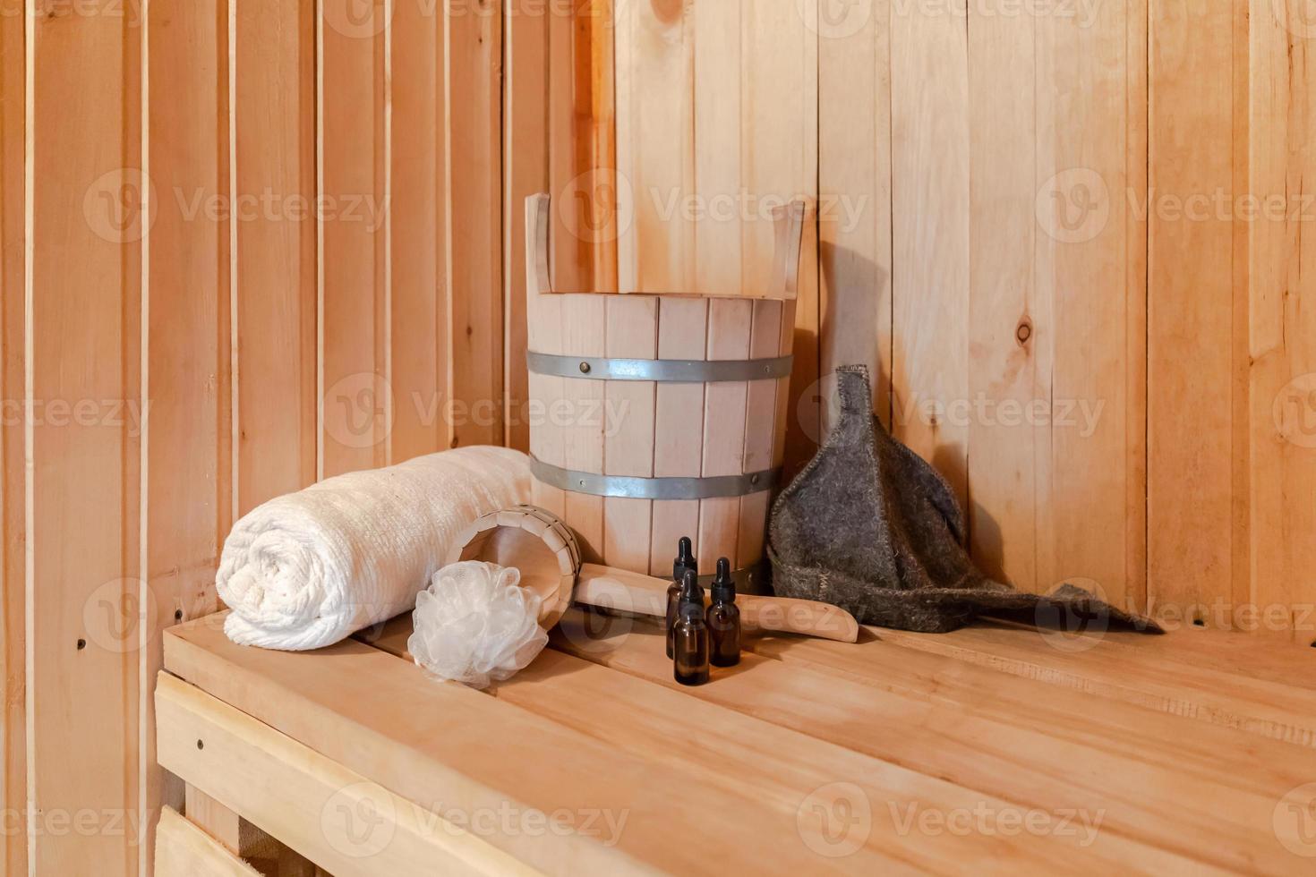 Traditional old Russian bathhouse SPA Concept. Interior details Finnish sauna steam room with traditional sauna accessories set basin towel aroma oil scoop felt. Relax country village bath concept. photo