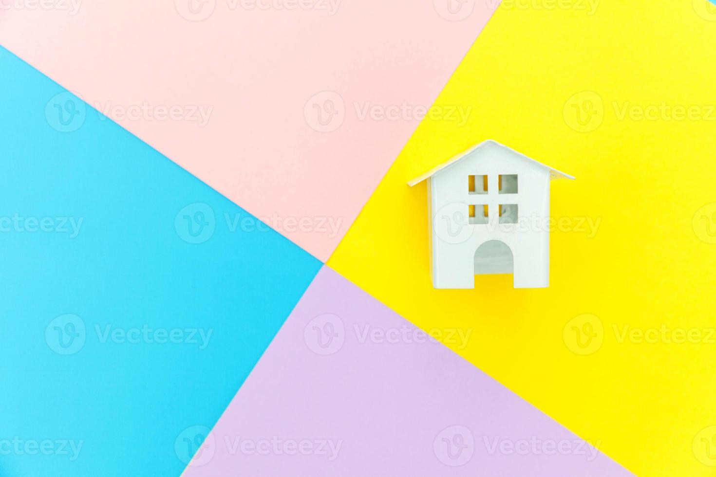 Simply design miniature white toy house isolated on blue yellow pink purple pastel colorful trendy geometric background Mortgage property insurance dream home concept. Flat lay top view copy space. photo