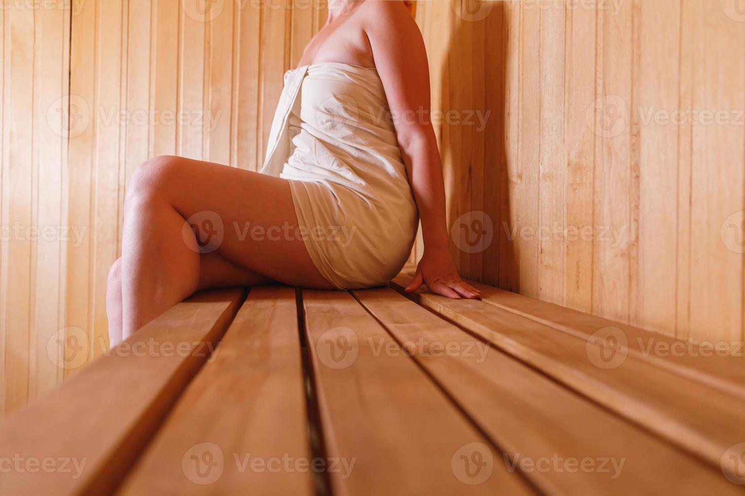 Traditional old Russian bathhouse SPA Concept. Woman in towel relaxing in traditional Finnish sauna interior steam room. Relax country village bath concept. photo