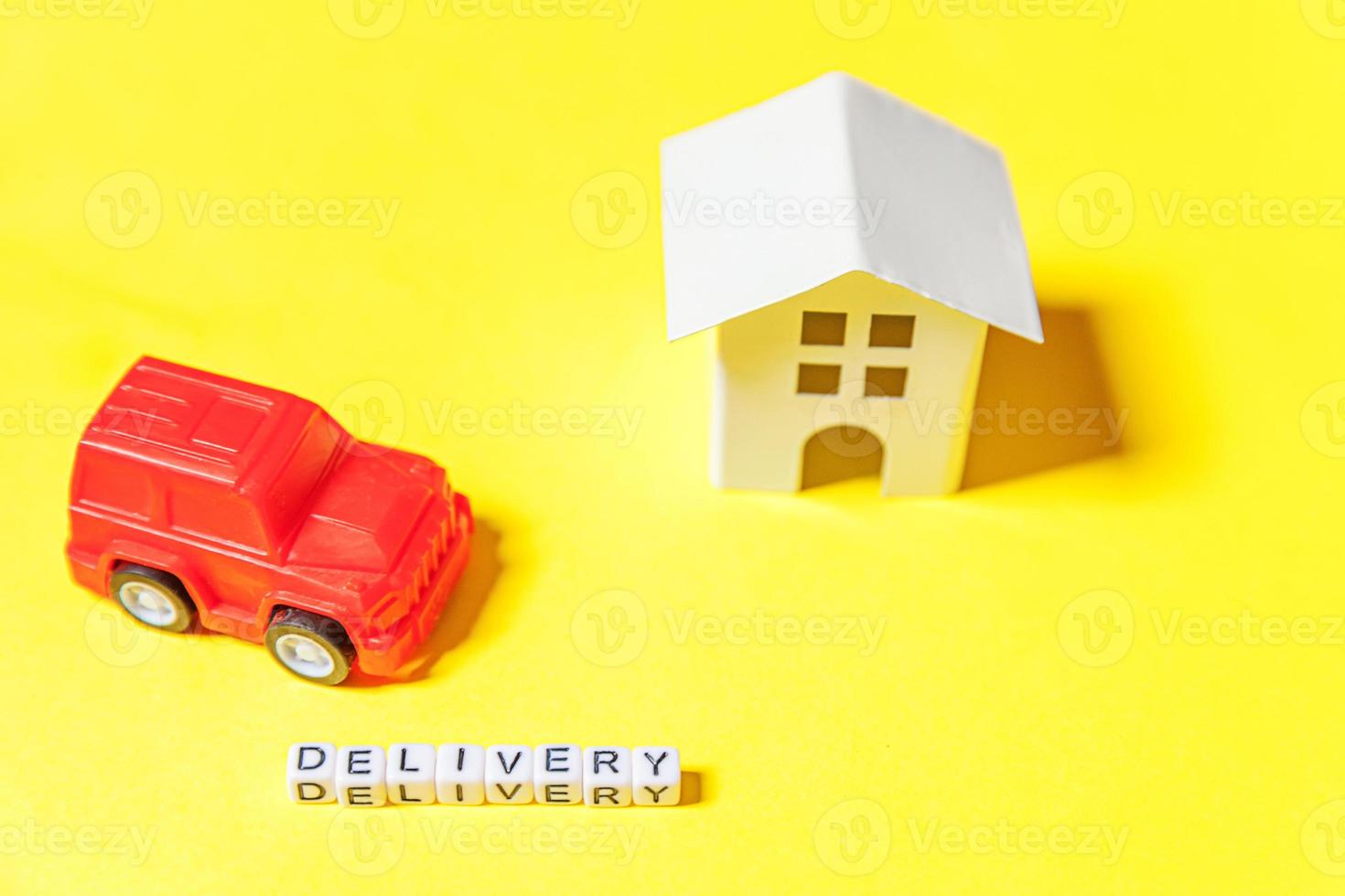 Simply design red toy car white house and inscription DELIVERY word isolated on yellow colorful background. Internet shopping online purchase e-commerce packages delivery service concept Copy space photo