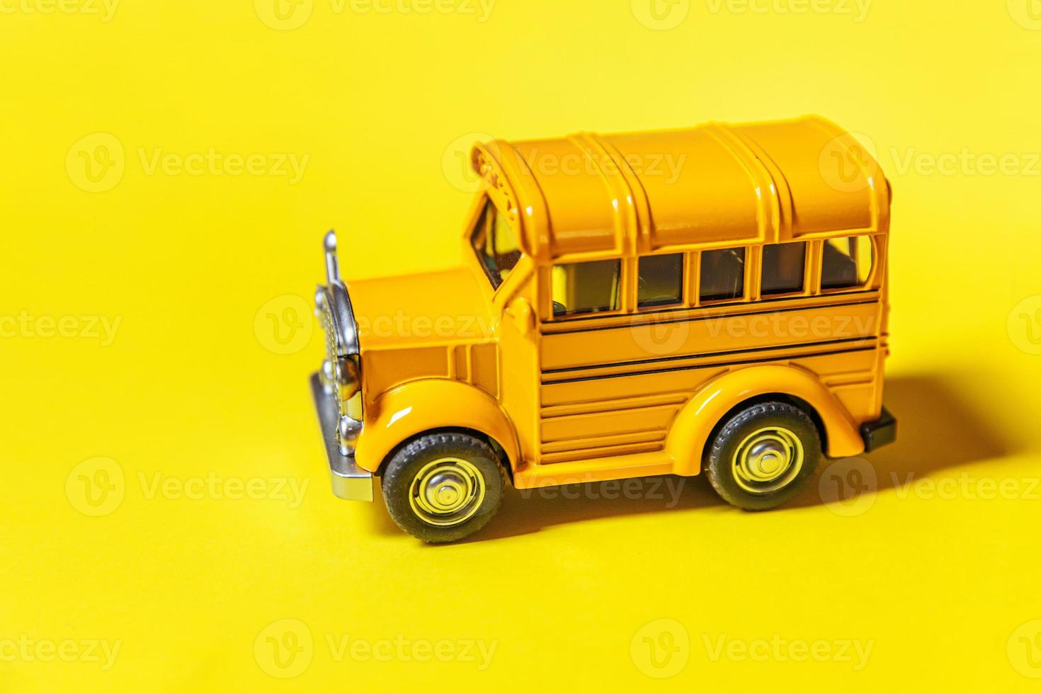 Simply design yellow classic toy car school bus isolated on yellow colorful background. Safety daily transport for kids. Back to school concept. Education symbol, copy space photo