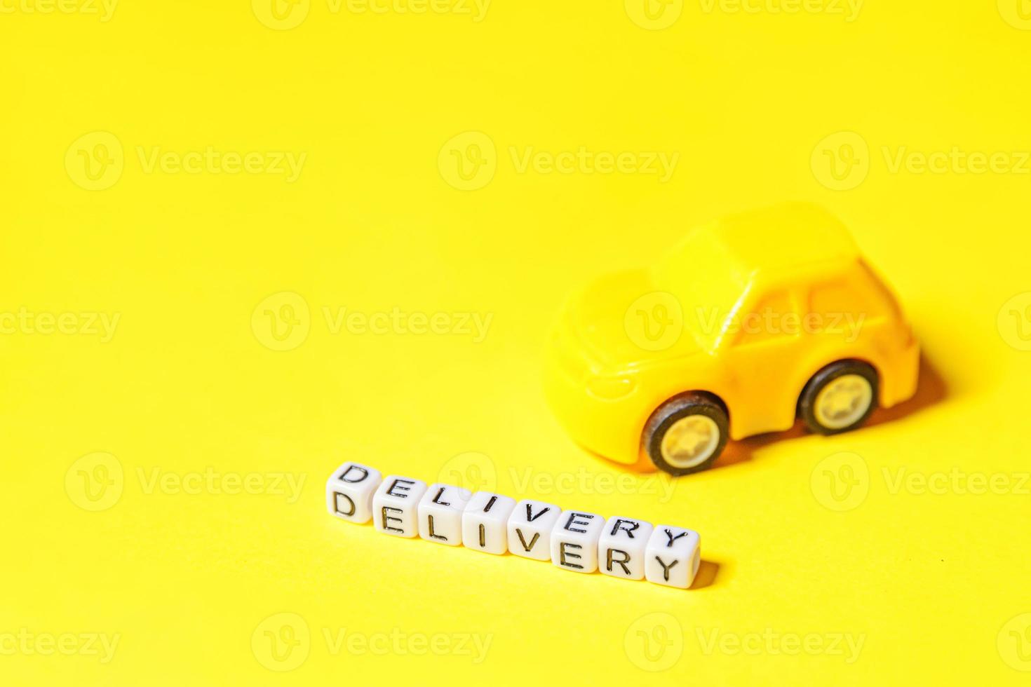 Simply design yellow toy car and inscription DELIVERY word isolated on yellow colorful background. Internet shopping online purchase e-commerce packages delivery service concept Copy space photo