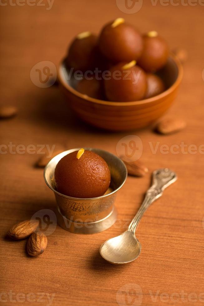 Gulab Jamun in bowl and copper antique bowl with spoon. Indian Dessert or Sweet Dish. photo