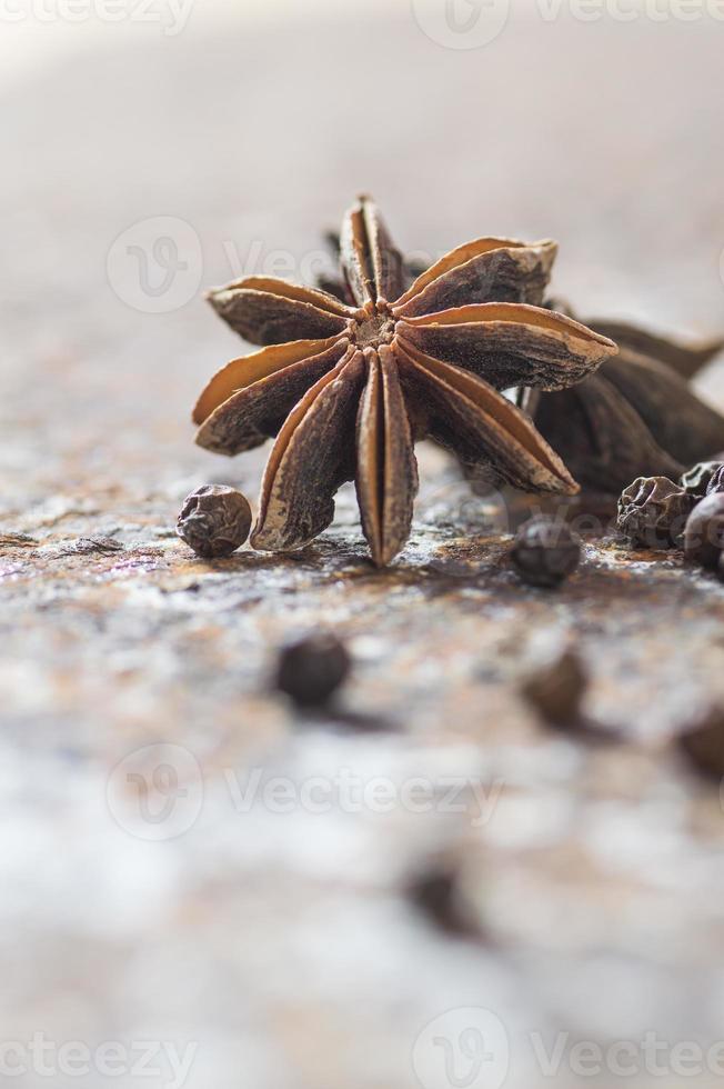 especias y hierbas. ingredientes de comida y cocina. estrellas de anís y granos de pimienta negra sobre fondo texturizado foto