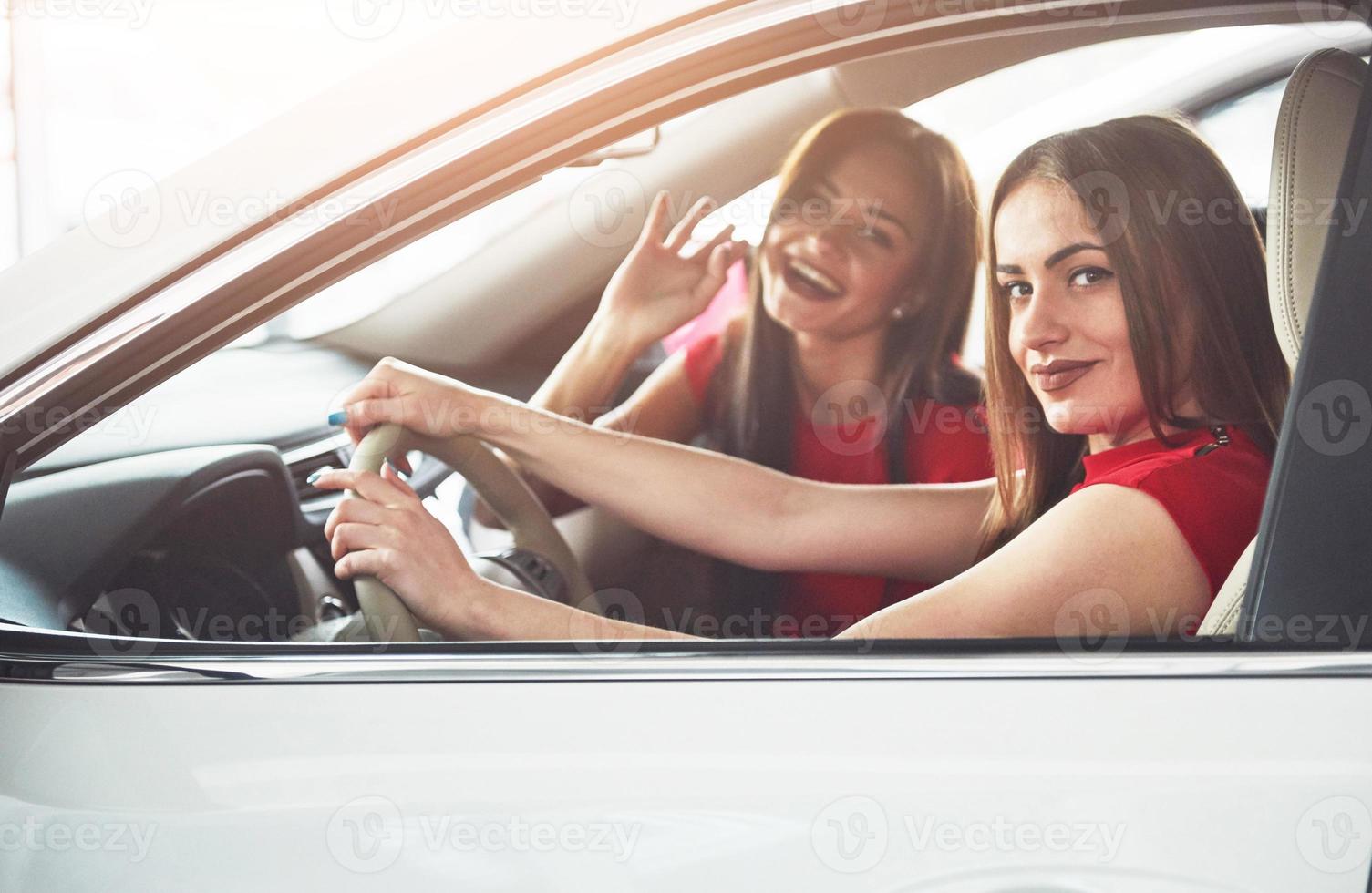 disfrutando de viajar. bellas gemelas sentadas en los asientos delanteros y sonriendo mientras posan en cámara foto