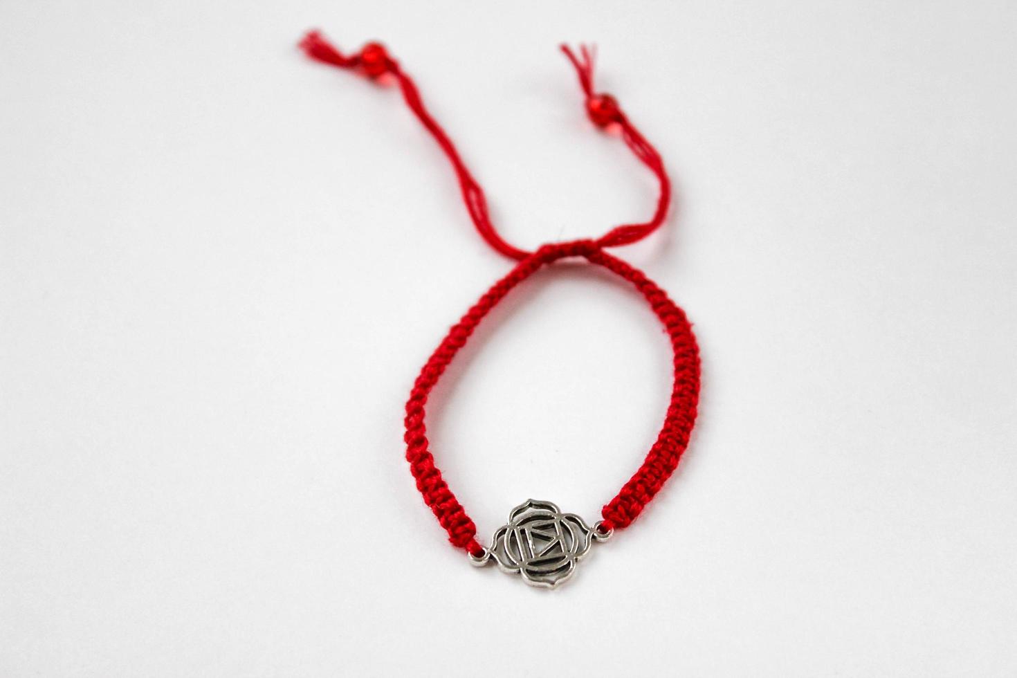 red braded bracelet with chakra muladhara on white background photo