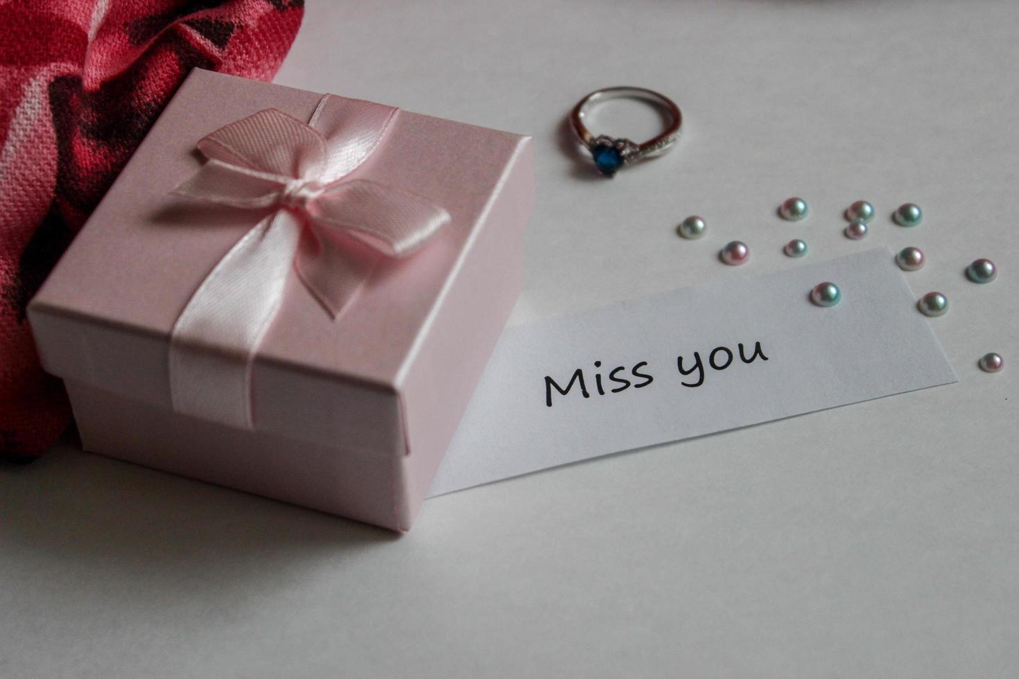 Note miss you with gift box, ring and handkerchief on white background photo