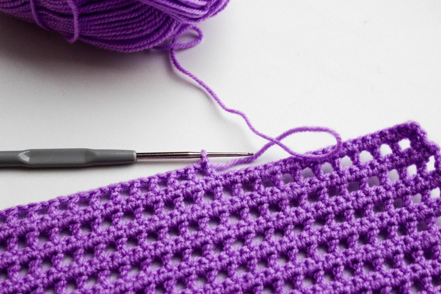 Ball of yarn, crochet hook and a piece of knitted linen photo