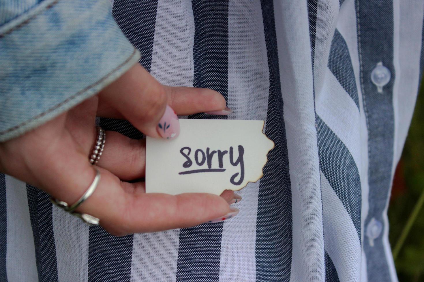 woman in jeans jacket and dress holding apology note photo