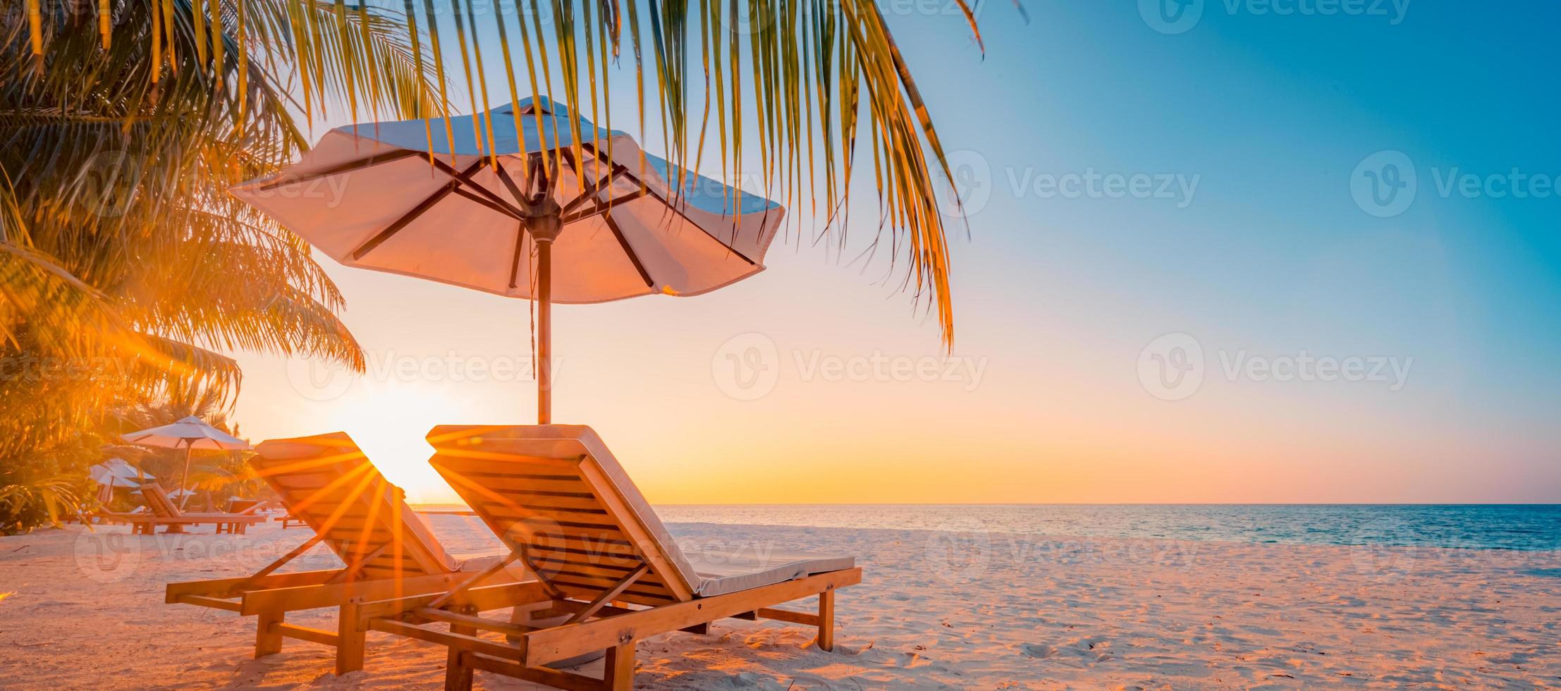 rayos panorámicos de puesta de sol de playa tropical, dos tumbonas, tumbonas, sombrilla bajo palmera. arena blanca, horizonte de la costa del mar, cielo crepuscular colorido, pancarta tranquila y relajante. hotel inspirador en la playa foto