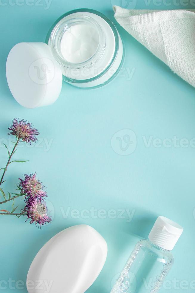 Cosmetic products and dry flowers on blue background. photo