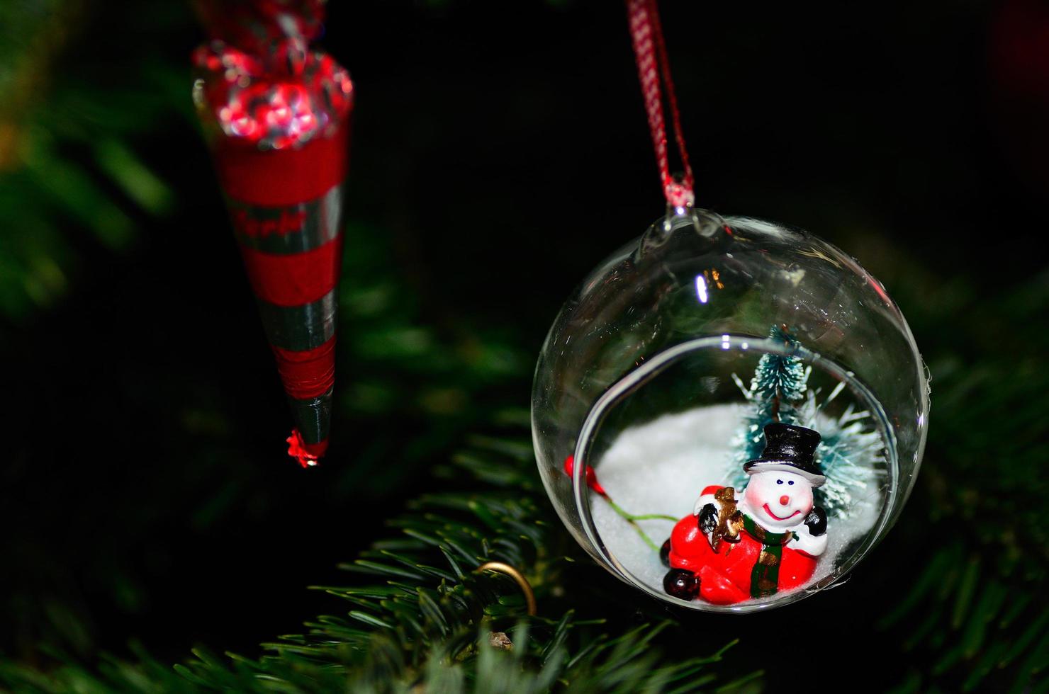 muñeco de nieve en bola en el árbol de navidad foto