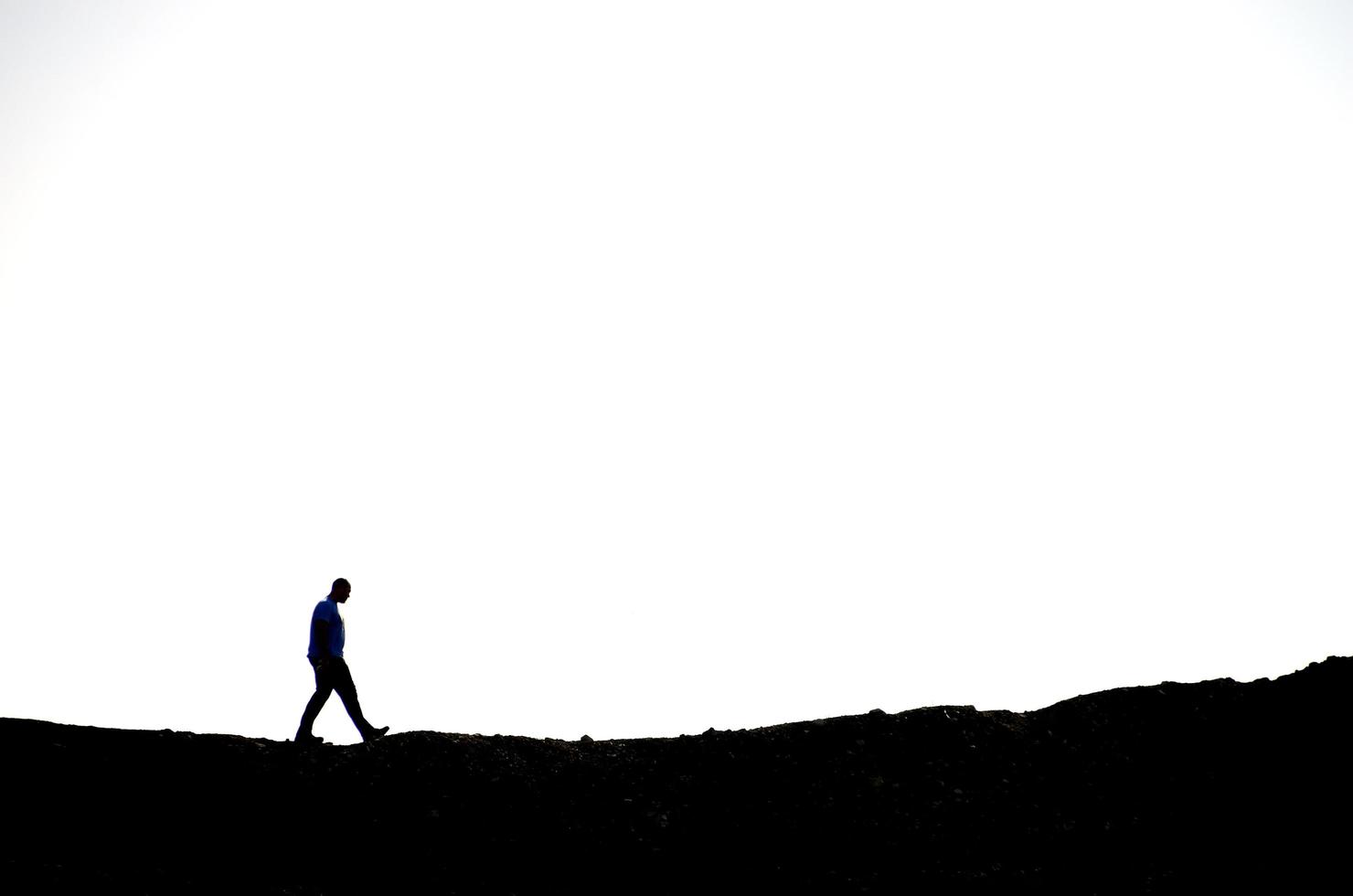 man hiking on a mountain with white sky photo