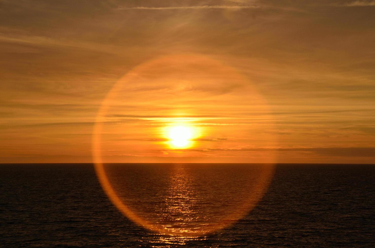 sunset at sea with ring reflection of sun photo