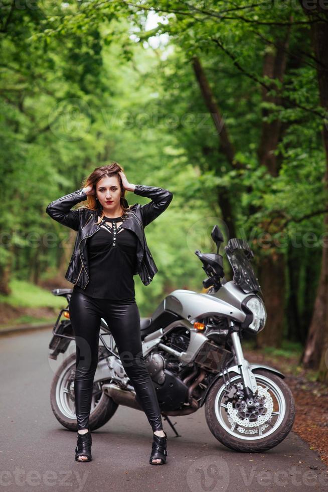 An attractive sexy girl on a sports motorbike posing outside photo